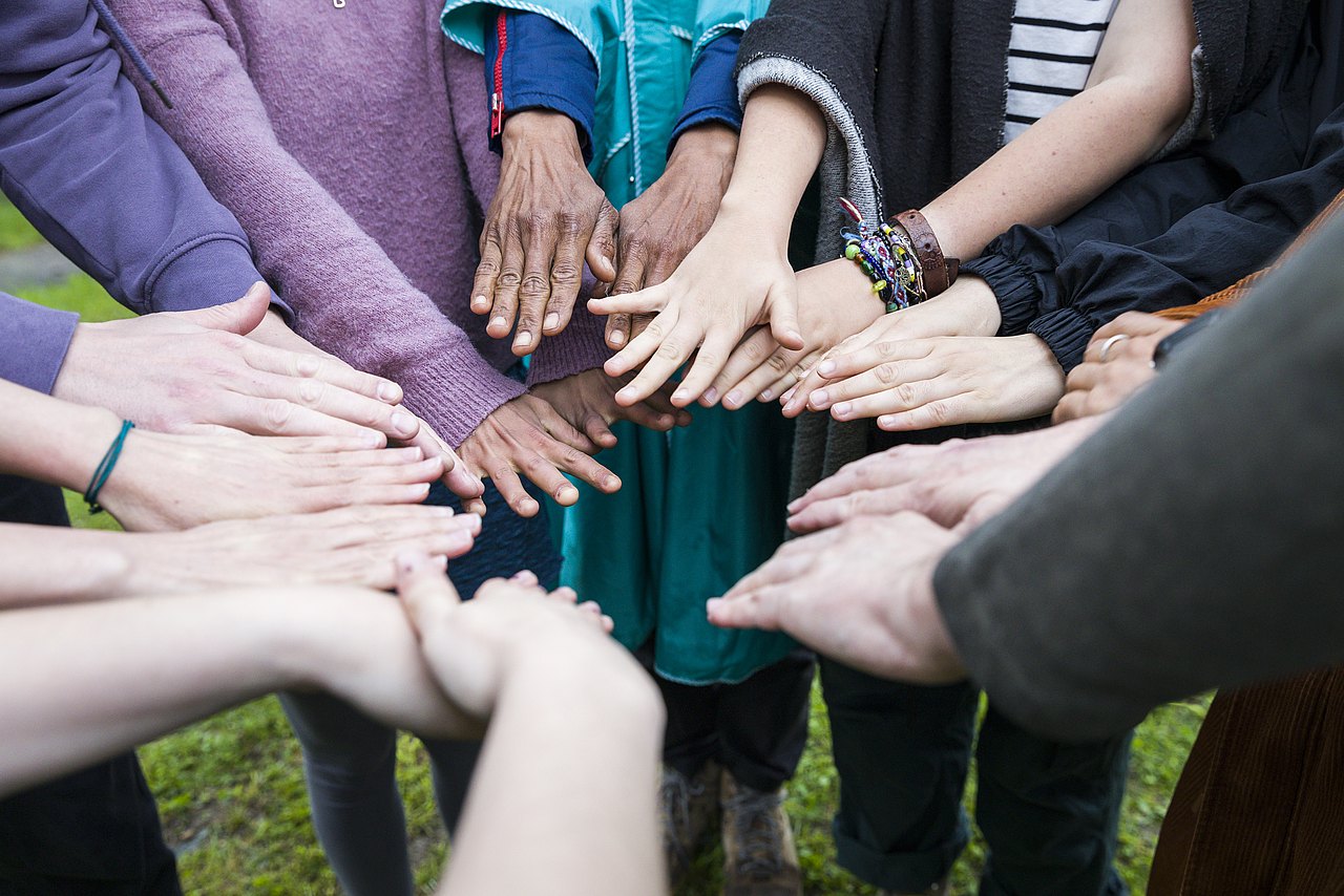 Verschiedene Hände, die in einem Kreis übereinandergelegt sind.