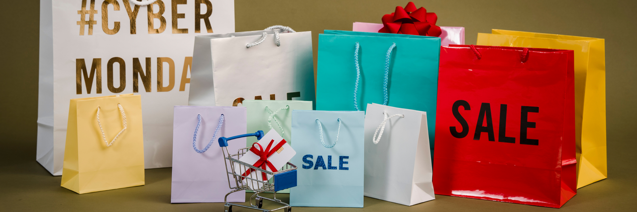 mehrere Einkaufstaschen mit Aufschriften wie "Sale" und "Cyber Monday" stehen nebeneinander