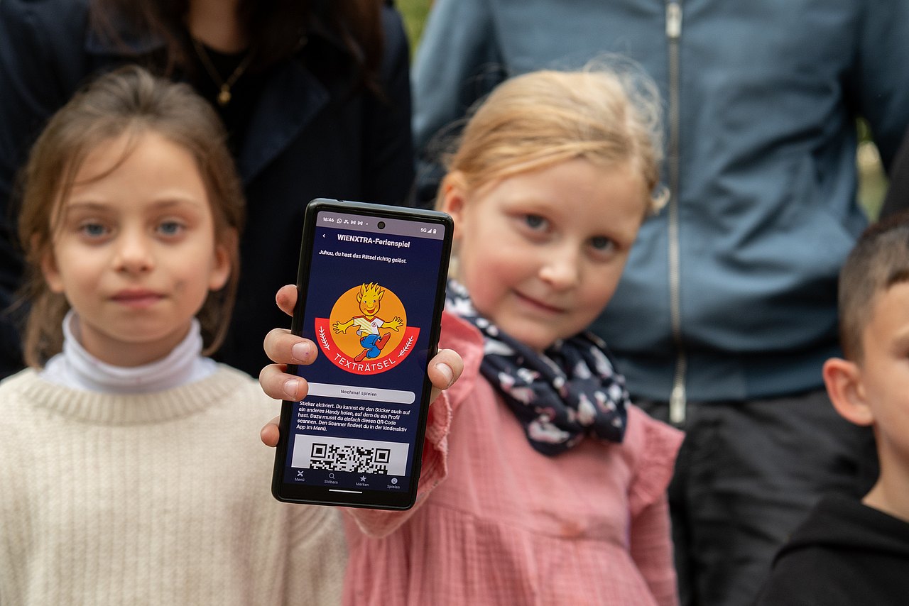 mehrere Kinder, eines hält ein Smartphone mit einem Holli-Sticker
