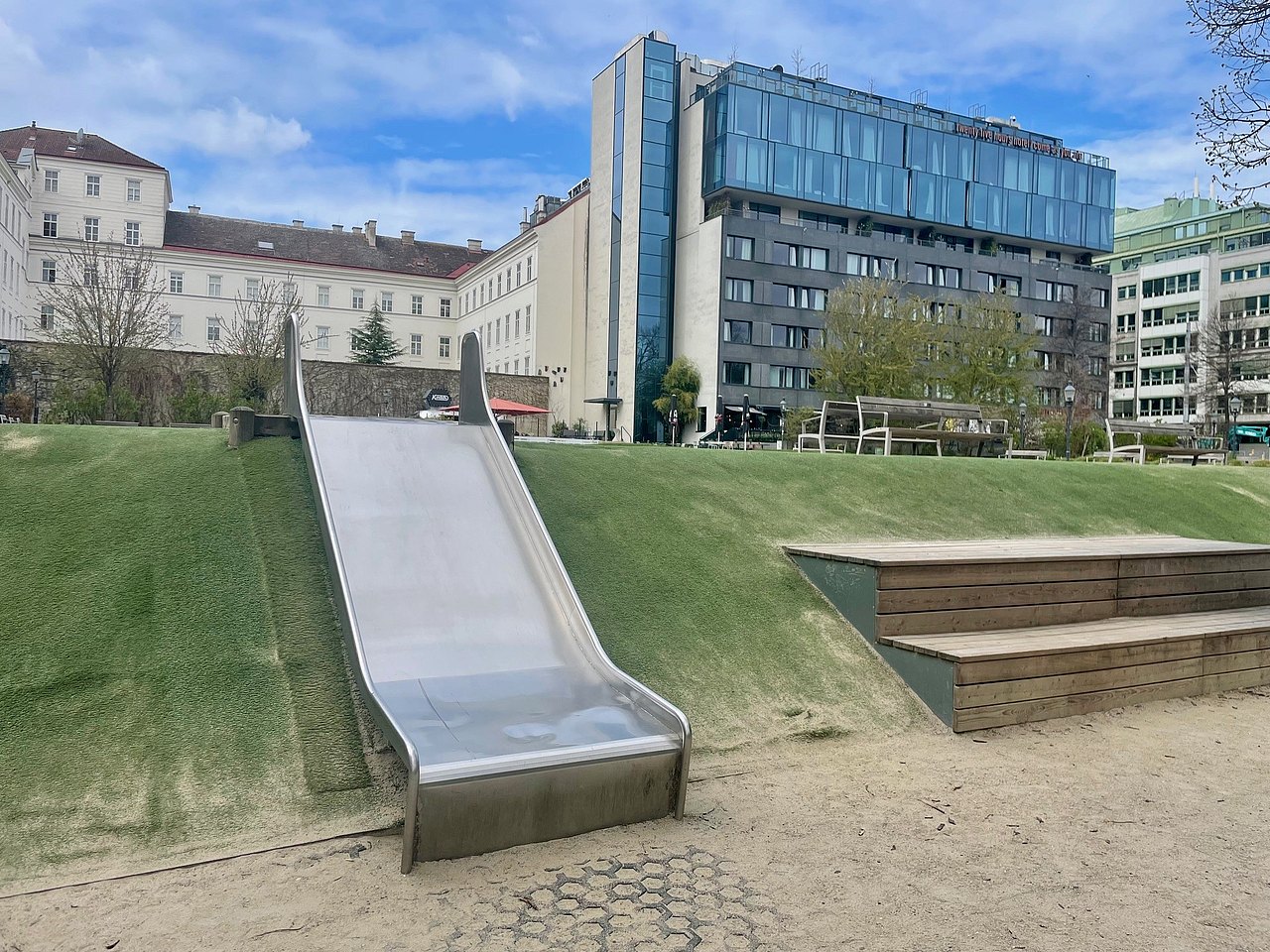 breite Bodenrutsche am Spielplatz Weghuberpark Im Vordergrund die breite Bodenrutsche, im Hintergrund das 25 Hours Hotel