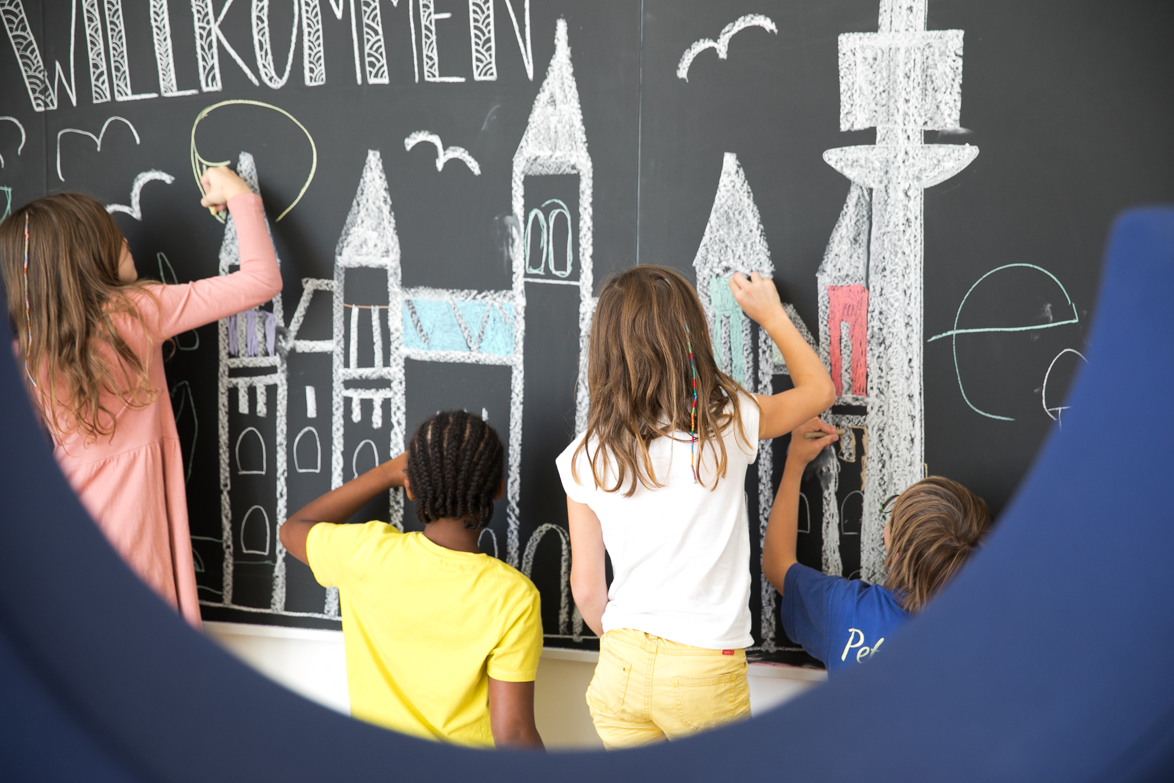 Kinder malen mit Kreide eine Stadt auf eine Tafel