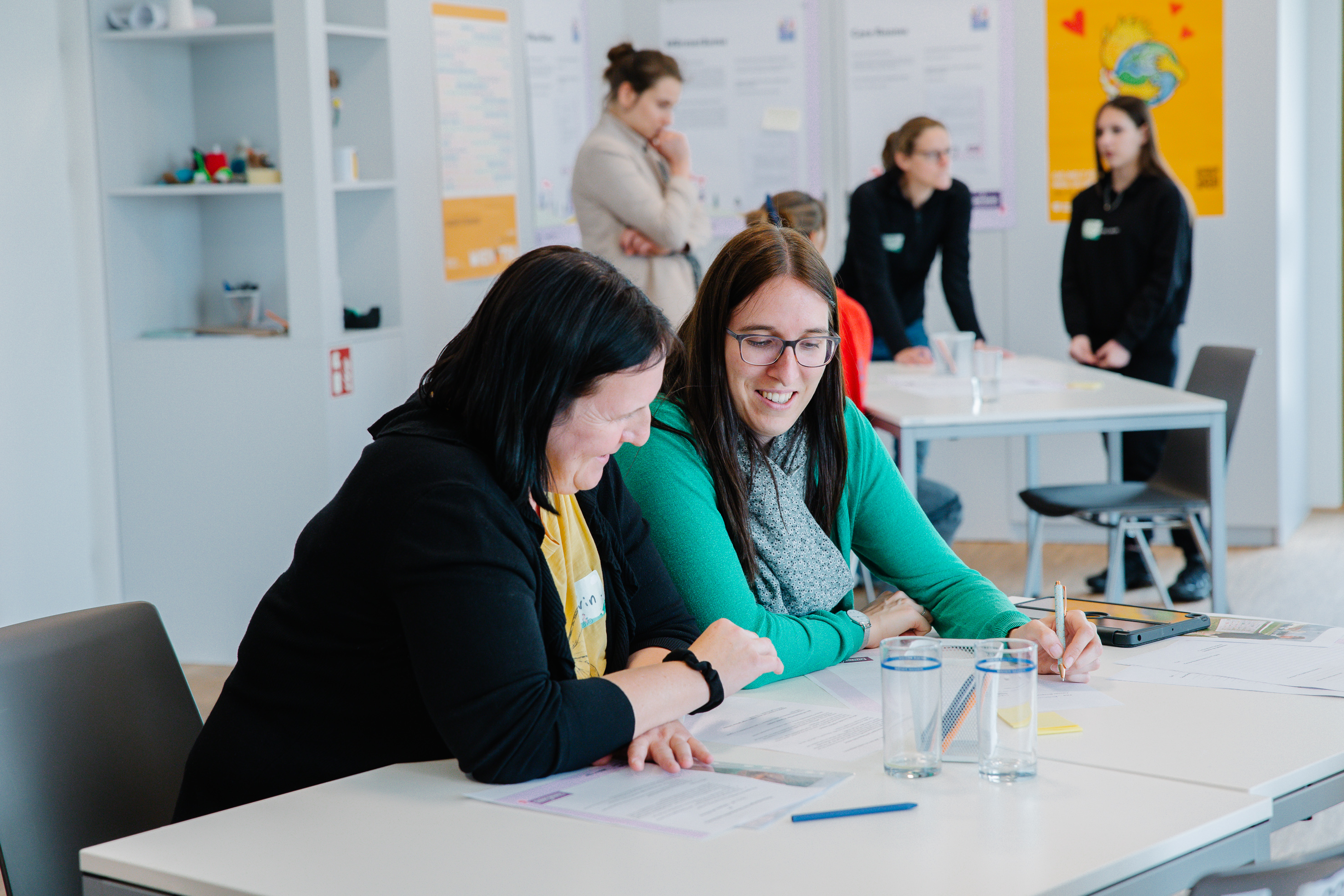 Personen sitzen an einem Tisch und besprechen sich