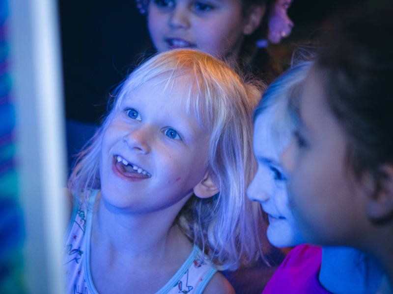 digtale Welten im GEDS Pavillion Kinder die von Blaulicht angestrahlt vor einem großen Bildschirm stehen